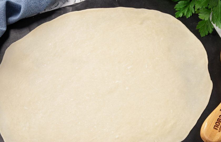 1. Этап. Ханум с овощами: Две из них накройте миской, чтобы не обветрились, а третью лепёшку раскатайте на посыпанном мукой столе в тонкий сочень. Удобнее делать это на силиконовом коврике или столе, смазанном растительным маслом.