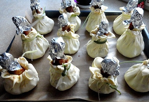 1. Этап. Курица в мешочке: И затем поднимая края теста, формируем мешочек вокруг куриной голени. Завязываем тесто нарезанными на полосочками перьями лука-порея. Куриные голени обернем фольгой, чтобы они не обгорели во время запекания.