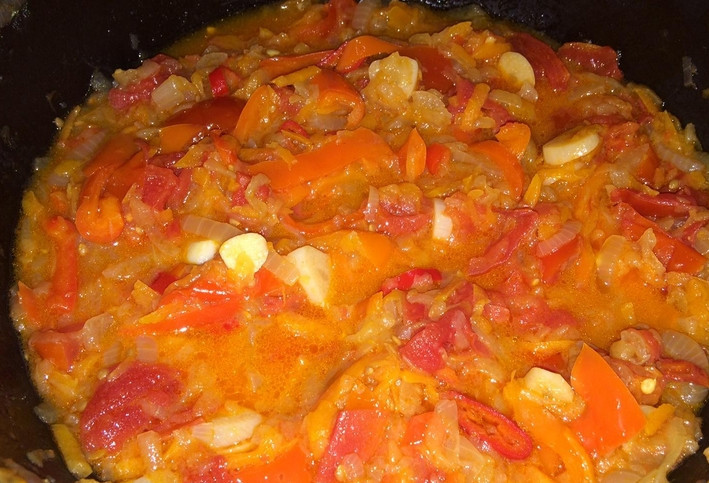 1. Этап. Аджика из помидоров и лука на зиму: Добавляем в казан зубчики чеснока и острый перец, очищенный от семян. Тушим еще 1 час. Когда овощи превратятся в пюре, добавьте соль, сахар и уксус. Перемешайте.