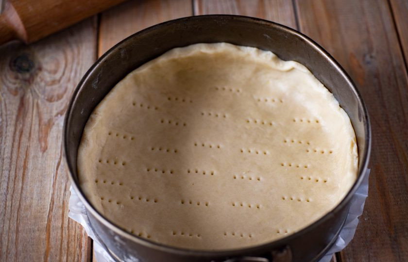 1. Этап. Тыквенный пирог классический: Охлажденное тесто раскатайте в пласт толщиной примерно в 0,5-0,7 мм. и выложите в форму, застеленную пергаментом для выпекания. Сформируйте из теста основу с бортиками высотой примерно в 4 см., наколите вилкой горизонтальную поверхность теста.