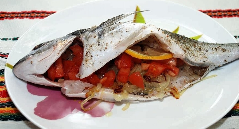 1. Этап. Дорада в фольге: 4. В поджаренный лук положите помидоры без шкурки. Ошпарьте кипятком помидор, чтобы ее удалить. Перемешайте с луком. Потомите под крышкой. Затем переложите получившуюся начинку в свободную брюшную полость и в голову. Добавьте пару кружочков лимона.