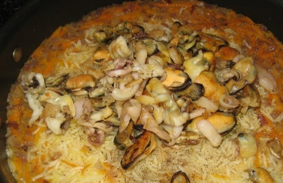 1. Этап. Плов с морепродуктами: Открываем крышку и добавляем обжаренные морепродукты, измельченный чеснок и при необходимости еще соль и перец.