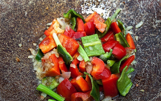 1. Этап. Паэлья в казане: 2. Тем временем вымыть, очистить от хвостиков и семян болгарский перец. Нарезать небольшими кусочками. В рецепт приготовления паэльи в казане можно также использовать небольшой кусочек острого перца. Когда лук обжарился добавить к нему перец.