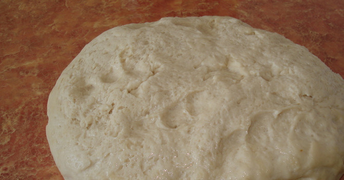 1. Этап. Пирожки с горохом в духовке: 4. Смажьте стол растительным маслом и хорошенько вымешайте тесто.