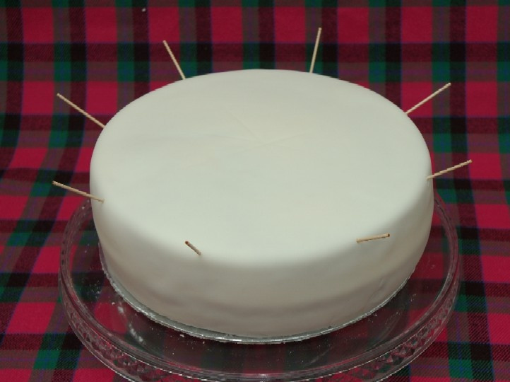 1. Этап. Торт Шикарный: 10. Белой мастикой обтяните тортик, оставьте его на пару часов. После воткните по периметру тортика зубочистки или деревянные палочки.