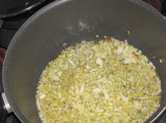 1. Этап. Плов из баранины с помидорами: Для начала мы нагреваем в глубокой толстостенной посуде немного растительного масла, затем выкладываем в него тертый имбирь, измельченный чеснок (3 дольки) и нарезанную мелко половину луковицы. Жарим все, помешивая, до золотистого цвета.