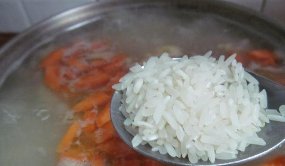 1. Этап. Сырный суп с крабовыми палочками: Картофель промойте и очистите. Нарежьте его кубиками и отправьте в бульон. Морковь также поскоблите ножом, вымойте, нарубите кружочками и выложите в кастрюльку. То же самое проделайте с репчатым луком. В завершение положите в кипящий бульон рис. Варите все ингредиенты до готовности (около получаса).