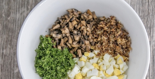 1. Этап. Салат новогодний из грибов: К грибам и луку добавьте нарезанные произвольно вареные яйца и измельченный укроп.