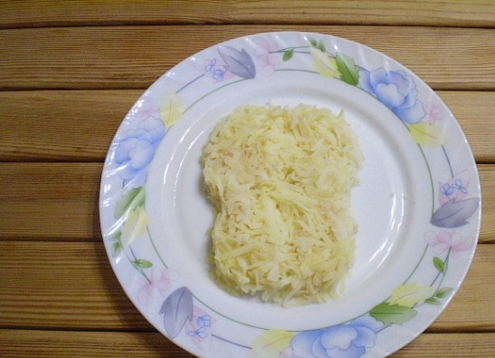 1. Этап. Селедка под шубой в виде обезьянки: Представьте себе, как будет выглядеть ваша обезьянка. И начните выкладывать тертый картофель в форме мордочки. Смажьте его майонезом, посолите и поперчите по вкусу.