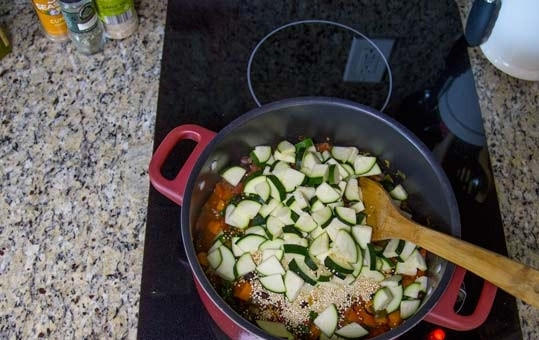 1. Этап. Перуанский суп с овощами и фасолью: 10. Выложите цукини, киноа и влейте воду. Доведите до кипения и варите 20 минут на среднем огне.