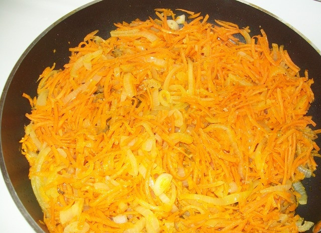 1. Этап. Треска с картофелем в духовке: Очистить лук и морковь. Обжарить на растительном масле до золотистого цвета.