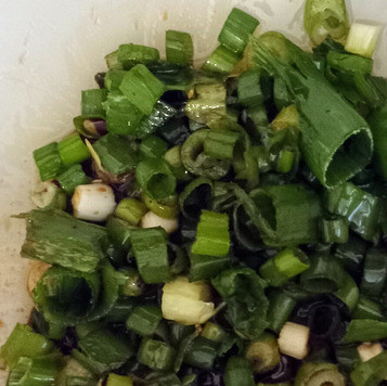 1. Этап. Салат кукурузный хияши: Как можно мельче нарезать зелёный лук и поместить его в салатницу вместе с 4 столовыми ложками оливкового масла, уксусом и двумя чайными ложками соевого соуса. Отложить в сторону.