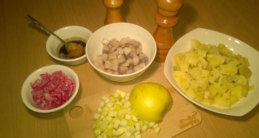 1. Этап. Салат из сельди и картофеля: 1. Подготовьте ингредиенты. Картофель отварите в мундирах, остудите и порежьте (не мелко). Лук заранее порежьте и замаринуйте на 1 час. Для маринада вам понадобятся: по 50 мл. воды кипяченой и уксуса, щепотка соли, 1 кофейная ложка сахара. Перед приготовлением салата лук отцедите. Сельдь порежьте. Яблоко тоже порежьте, главное — не крупно. Для соуса все ингредиенты тщательно смешайте.