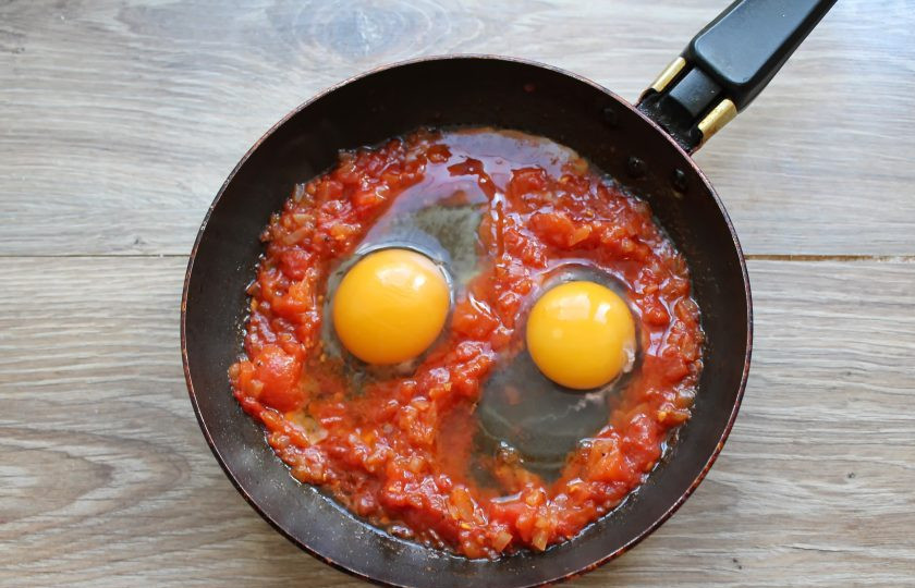 1. Этап. Яичница с консервированными помидорами: В томатной массе сделайте два углубления и вбейте в них по одному яйцу. Яйца посолите, поперчите.