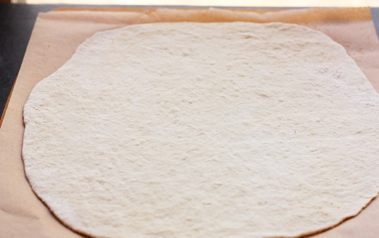 1. Этап. Пицца на противне: 2. Раскатайте тонко тесто и выложите на пергамент. Тем временем натрите твердый сыр на крупной терке.