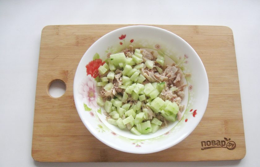 1. Этап. Салат Воронье гнездо: Огурец помойте, очистите и нарежьте кубиками. Выложите в салат.