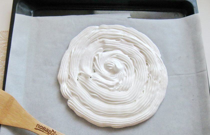 1. Этап. Безе Павлова: Нарисуйте на пергаменте круг диаметром 20-22 сантиметра. С помощью кулинарного мешка с насадкой выложите безе, полностью заполняя круг.