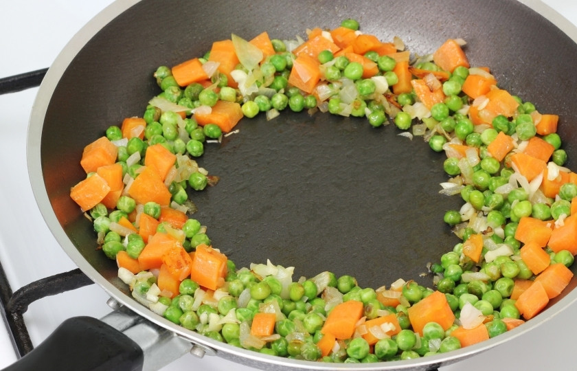 1. Этап. Жареный рис с курицей: Сначала немного обжарьте овощи на сковороде. До мягкости. Затем распределите их в форму кольца по стенкам сковороды.