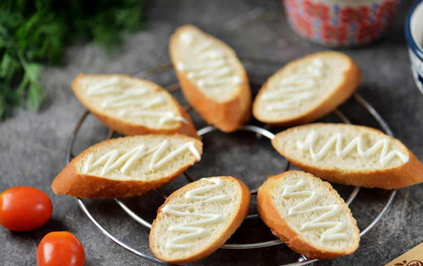 1. Этап. Канапе с селедкой и помидорами: Поджаренный хлеб остудите, слегка полейте майонезом.