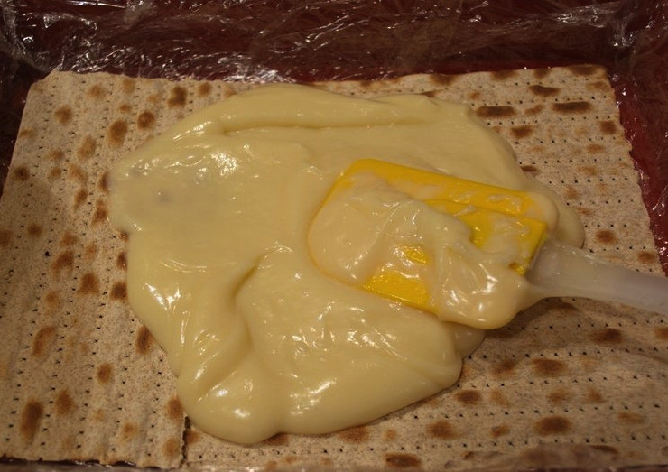 1. Этап. Торт из мацы без выпечки: Когда крем остынет, влейте туда оствшееся молоко и добавьте ванилин. Хорошо перемешайте и оставьте на 10 минут, затем снова перемешайте. В форму для торта положите пищевую плёнку. Это нужно, чтобы крем не растёкся. Положите на дно листы мацы, чередуйте их со слоями крема. Не жалейте крема на слои, иначе торт получится сухим. Верхний слой можно посыпать крошкой из мацы. Сформированный торт закройте плёнкой и отправьте в холодильник на сутки. После этого его можно будет кушать.