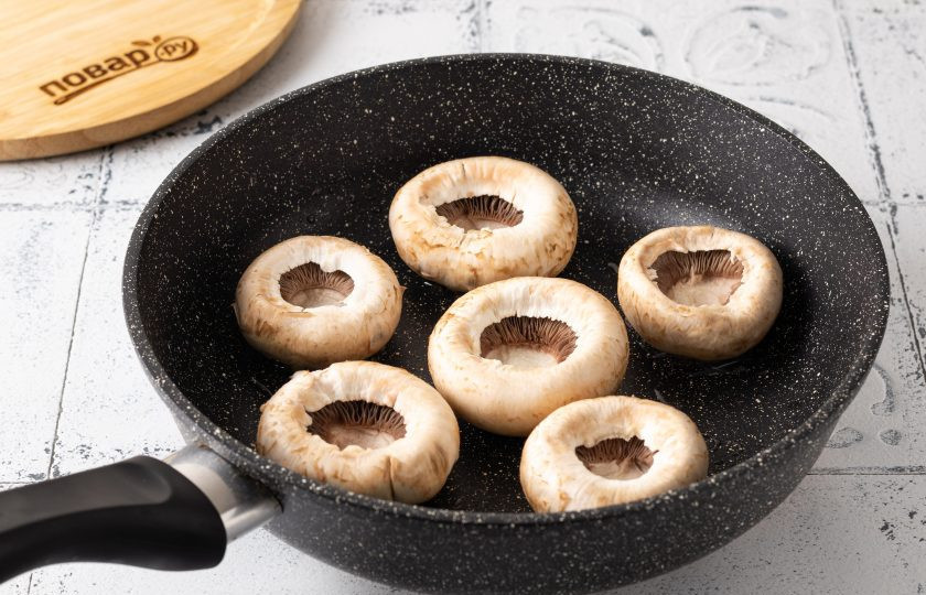 1. Этап. Шампиньоны с творожным сыром и зеленью: Обжарьте шляпки шампиньонов с растительным маслом до легкого золотистого цвета с двух сторон. Примерно на это уйдёт 10-12 минут. Остудите шляпки.