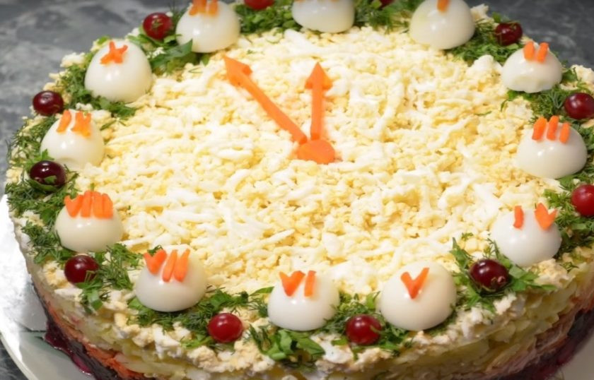 1. Этап. Салат Новогодняя ночь с селедкой: 12. Яйца разрезаем пополам и выкладываем желтком вниз, сверху выкладываем морковь в виде циферблата и украшаем все зеленью.