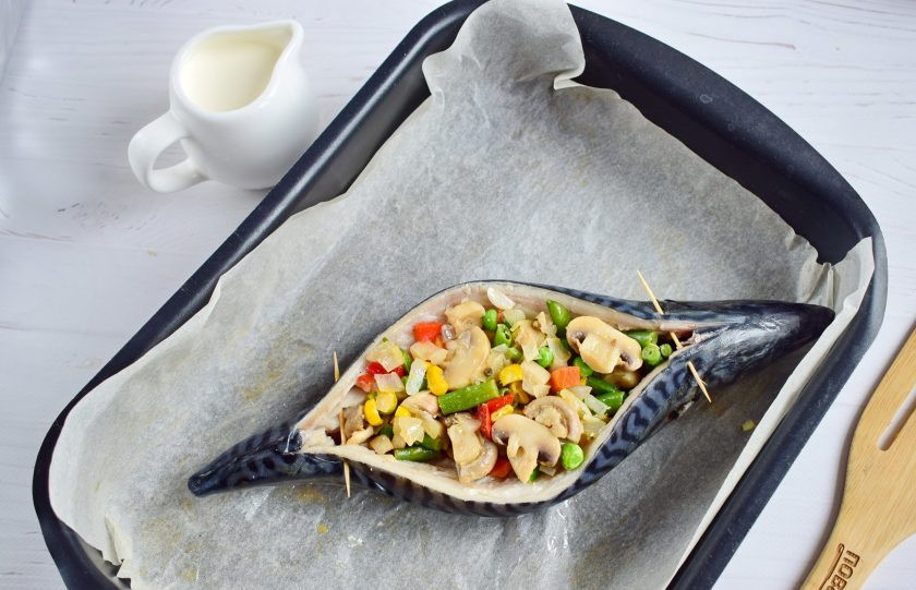 1. Этап. Скумбрия «Сливочная неженка»: Разрезы на спинке рыбы соедините на концах зубочистками. Разместите тушку на животе на противне с пергаментом для выпечки. Наполните скумбрию начинкой.