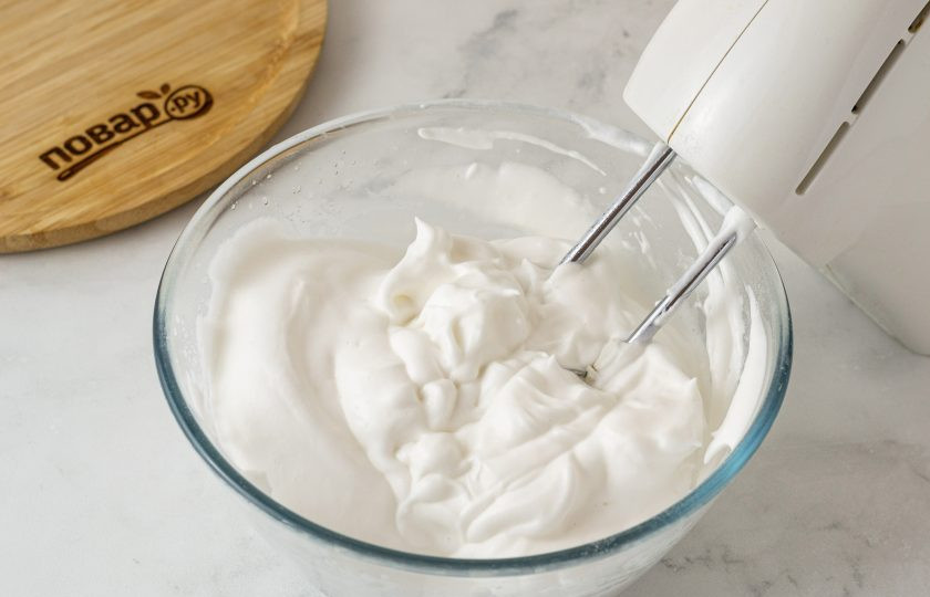 1. Этап. Постный торт Птичье молоко: Затем очень тонкой струйкой влейте кипящую смесь в миску со взбитой аквафабой. Одновременно с этим продолжайте взбивать массу на высокой скорости. Масса должна стать плотнее и более гладкой.