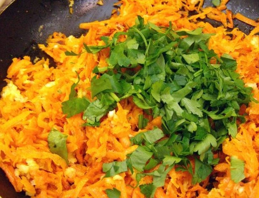 1. Этап. Синенькие с морковкой на зиму: Давленый чеснок и рубленую зелень разделите на части. Четверть от того и другого отложите, остальное добавьте к моркови и перемешайте.