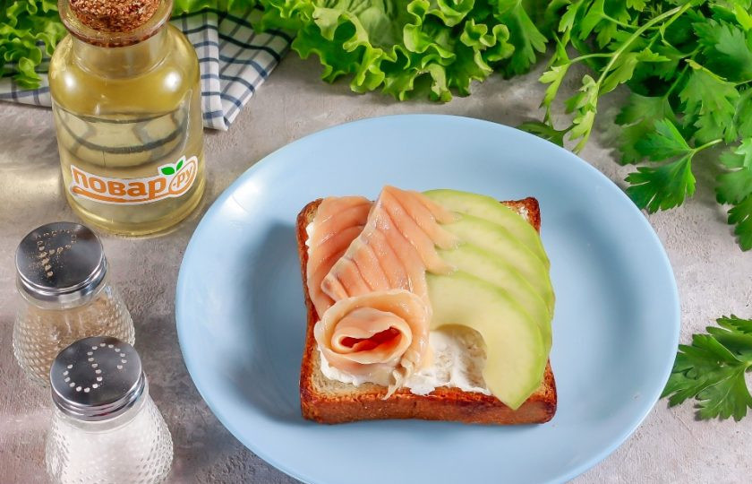 1. Этап. Тост с авокадо, соленой семгой и яйцом пашот: Выложите слабосоленую рыбку на вторую половину тоста. По желанию сверните нарезку розочкой.