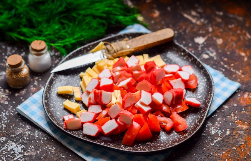 1. Этап. Салат из сыра, помидоров и крабовых палочек: Крабовые палочки нарежьте произвольно и добавьте в салат.