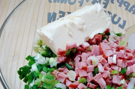 1. Этап. Перец, фаршированный колбасой и сыром: 4. Соедините в глубокой мисочке лук с колбасой. Добавьте размягченное сливочное масло и перемешайте.