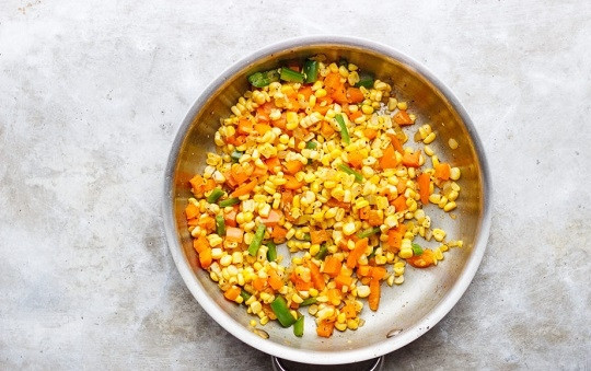 1. Этап. Быстрый суп из кукурузы: 1. На сковороде разогрейте оливковое масло. Выложите измельченный лук и чеснок. Обжарьте минутку, помешивая. Добавьте мелко нарезанный сладкий и острый перец, зерна кукурузы. Обжарьте 3-4 минуты.