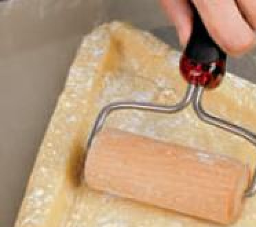 1. Этап. Пирог ягодный полосатый: Разогреть духовку до 180 0С. Противень накрыть антипригарным ковриком. Ни противень, ни коврик смазывать маслом не нужно. Тесто раскатать прямо на противне с помощью мини-скалки, придав тесту форму большого равнобедренного треугольника. Раскатывать от середины к краям так, чтобы края получились более толстыми. Руками сделать по краям аккуратные бортики высотой примерно 3 см. (При выпечке они немного растекутся и станут ниже.) Положить внутрь треугольника сухую фасоль или бобы, поставить в духовку и выпекать 20 мин. Вынуть корж, удалить фасоль. Края подровнять.