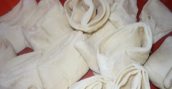 1. Этап. Пахлава индийская: Сверните каждый пласт в рулет, присыпав его мукой. Рулет разрежьте на кусочки примерно 2 см шириной. Края смажьте водой и немного распрямите каждый кусочек.