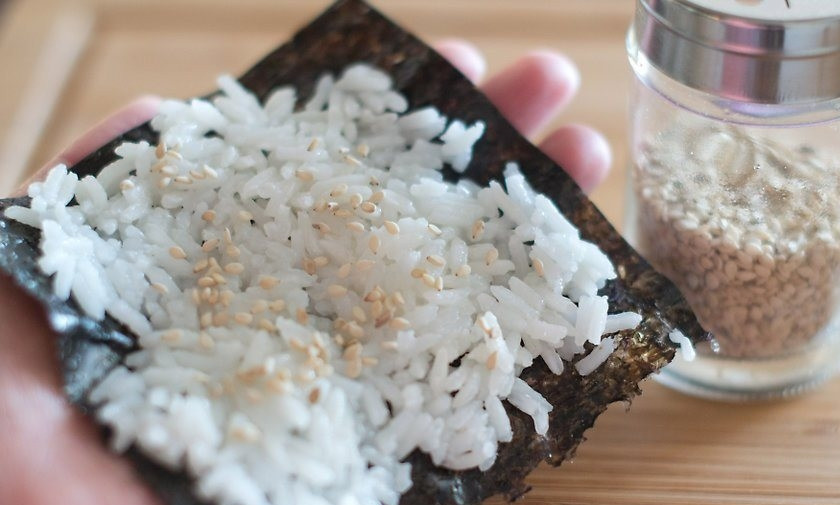 1. Этап. Суши простые: Предварительно отварите рис, очистите креветки, промойте и тонко нарежьте очищенный авокадо. Разрежьте нори на небольшие квадратики. Ложкой равномерно распределите на нем рис и присыпьте по желанию щепоткой кунжута.