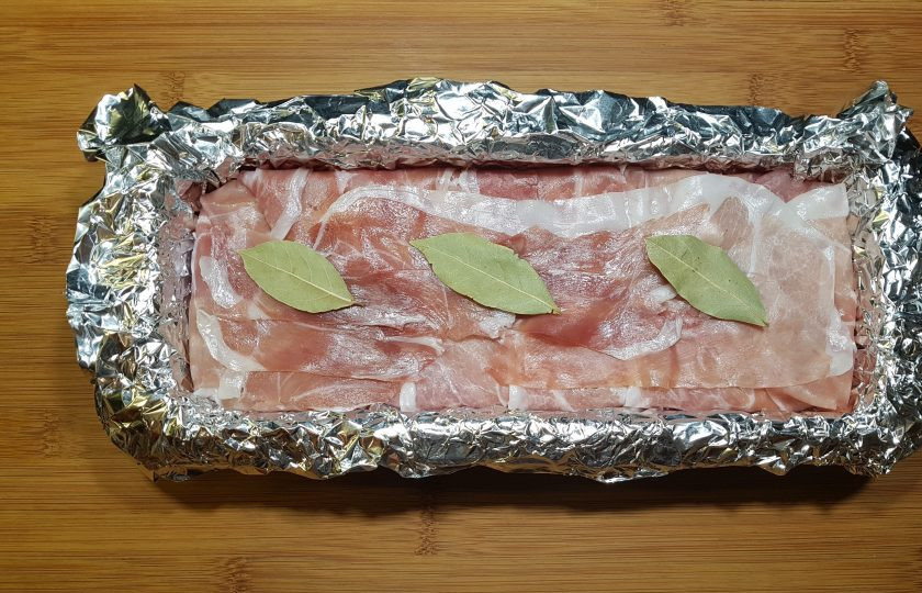 1. Этап. Террин из курицы с фисташками: Накройте фарш беконом. Сверху положите лавровые листики.