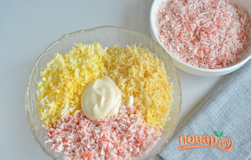 1. Этап. Салат-закуска Ёлочные шарики: На самой мелкой терке натрите сыр, яйца и крабовые палочки. Треть массы крабовой стружки отложите отдельно для панировки шариков. Добавьте майонез. Соль и другие специи по желанию, я не добавляла ничего, даже соль, на мой вкус было всего достаточно. Хорошо перемешайте.