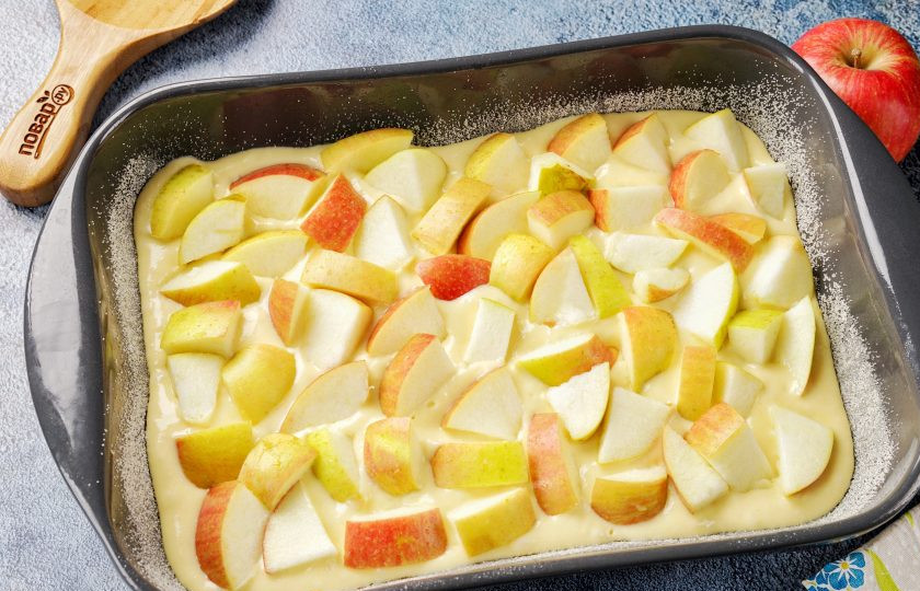 1. Этап. Заливной пирог на кефире с яблоками: Жаропрочную форму смажьте маслом. Дно и бока присыпьте мукой или манкой. Вылейте половину порции теста и равномерно разложите яблоки.