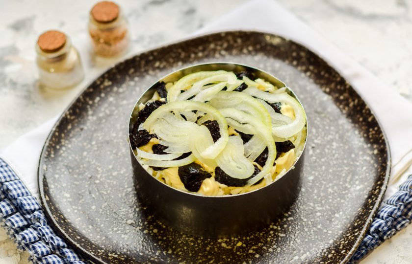 1. Этап. Салат Зимняя ночь: Поверх чернослива выложите нарезанный и маринованный лук.