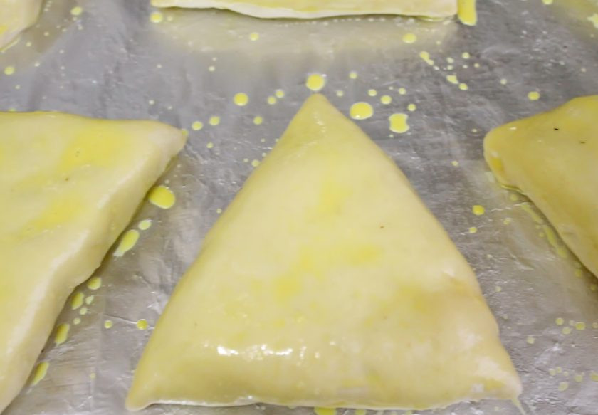 1. Этап. Пирожки с мясом и картошкой в духовке: Сделайте пирожки и выложите на смазанный растительным маслом противень швом вниз. Накройте чистой тканью и оставьте на 20 минут для подъема. Желток смешайте с молоком и смажьте поверхность пирожков.