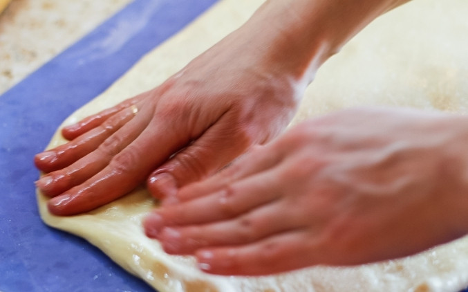 1. Этап. Тутманик: Отделяем от теста небольшой кусочек на украшение тутманика, а остальное тесто выкладываем на смазанную поверхность, поливаем его остатками масла и аккуратно растягиваем руками в тонкий пласт шириной в 1 сантиметр.