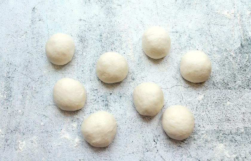 1. Этап. Несдобные пирожки: Переложите готовое тесто на присыпанный мукой стол и разделите его на одинаковые кусочки. Сформируйте из них шарики, накройте и дайте постоять 10-15 минут для подъема.