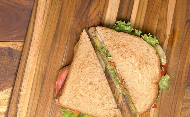 1. Этап. Бутерброды на шпажках: 11. Накройте бутерброд оставшимся ломтиком хлеба (стороной с майонезом вниз). Аккуратно прижмите и разрежьте бутерброд по диагонали на 2 части.