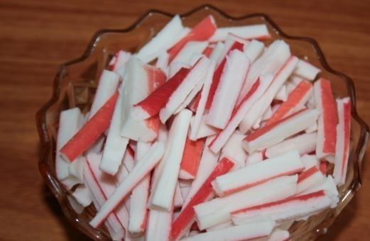 1. Этап. Салат с кальмарами и красной икрой: 5. Крабовые палочки очистите от пленок, нарежьте пополам, а после - брусочками.