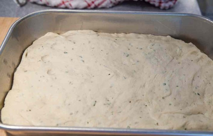 1. Этап. Итальянская фокачча с розмарином: 10. Смажьте растительным маслом противень и переложите в него тесто, распределите по всему противню, накройте его пленкой и оставьте еще на 30 минут.