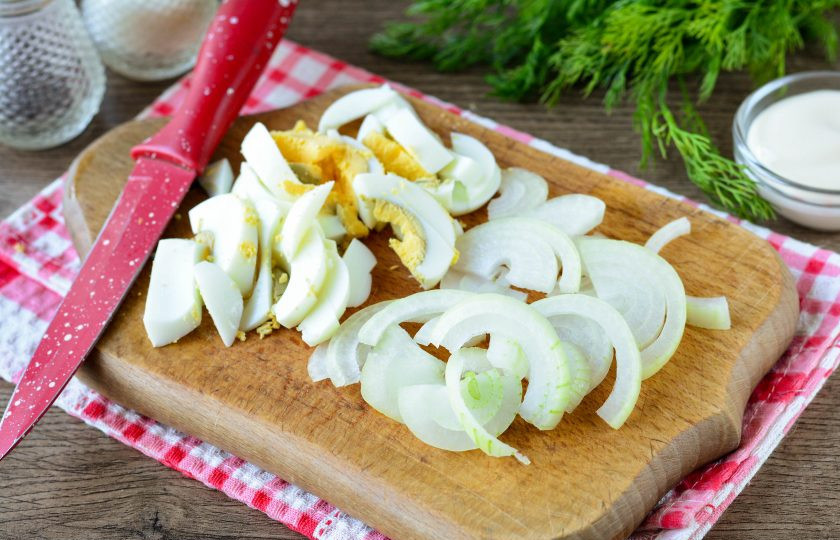 1. Этап. Салат Бахор с колбасой: Нарежьте полукольцами репчатый лук и сваренные вкрутую куриные яйца.