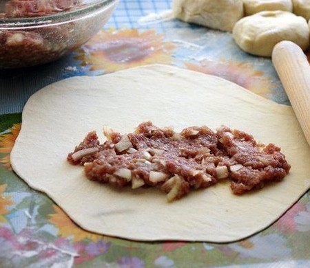 1. Stage. Chebureks on kefir: Divide the dough into pieces, roll out and lay the filling on one side.