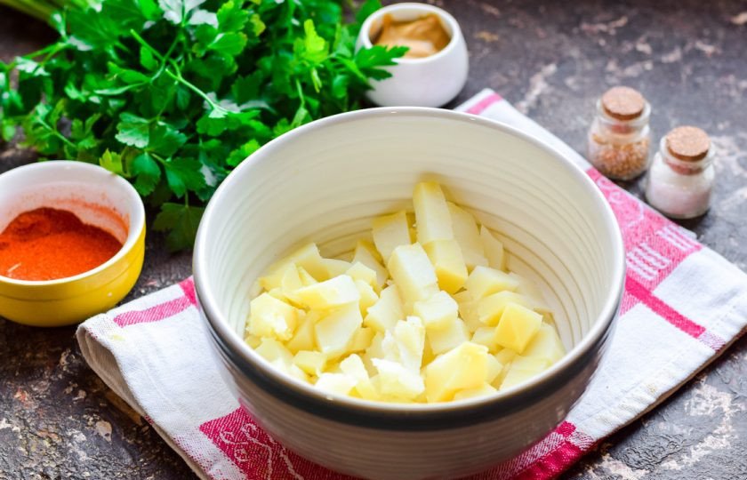 1. Этап. Салат с семгой и крабовыми палочками: Отварите картофель, почистите и нарежьте небольшими кубиками. Переложите картофель в салатник.