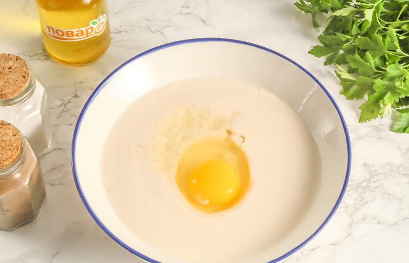 1. Этап. Вареники с сюрпризами на Старый Новый год: Сначала замесите тесто. В глубокую емкость влейте ряженку или кефир любой жирности, вбейте туда же куриное яйцо. Всыпьте щепотку соли и тщательно перемешайте.